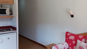A kitchen with a microwave, stove, and wooden cabinets. - 26m² Studio for 2 People PMR in Puy-Saint-Vincent (Puy-Saint-Vincent)