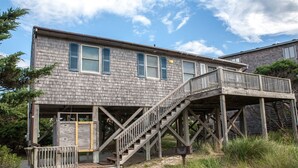 Ein zweistöckiges Haus mit einer Holzterrasse und einer Treppe zu einer überdachten Veranda.