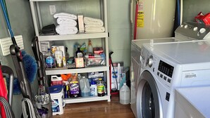 A laundry room with a washing machine, shelves with folded towels, cleaning supplies, and vacuum cleaners. - Upscale lodging duplex minutes from Glacier NP (Coram)