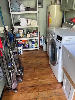 A laundry room with a washing machine, shelves with folded towels, cleaning supplies, and vacuum cleaners. - Upscale lodging duplex minutes from Glacier NP (Coram)