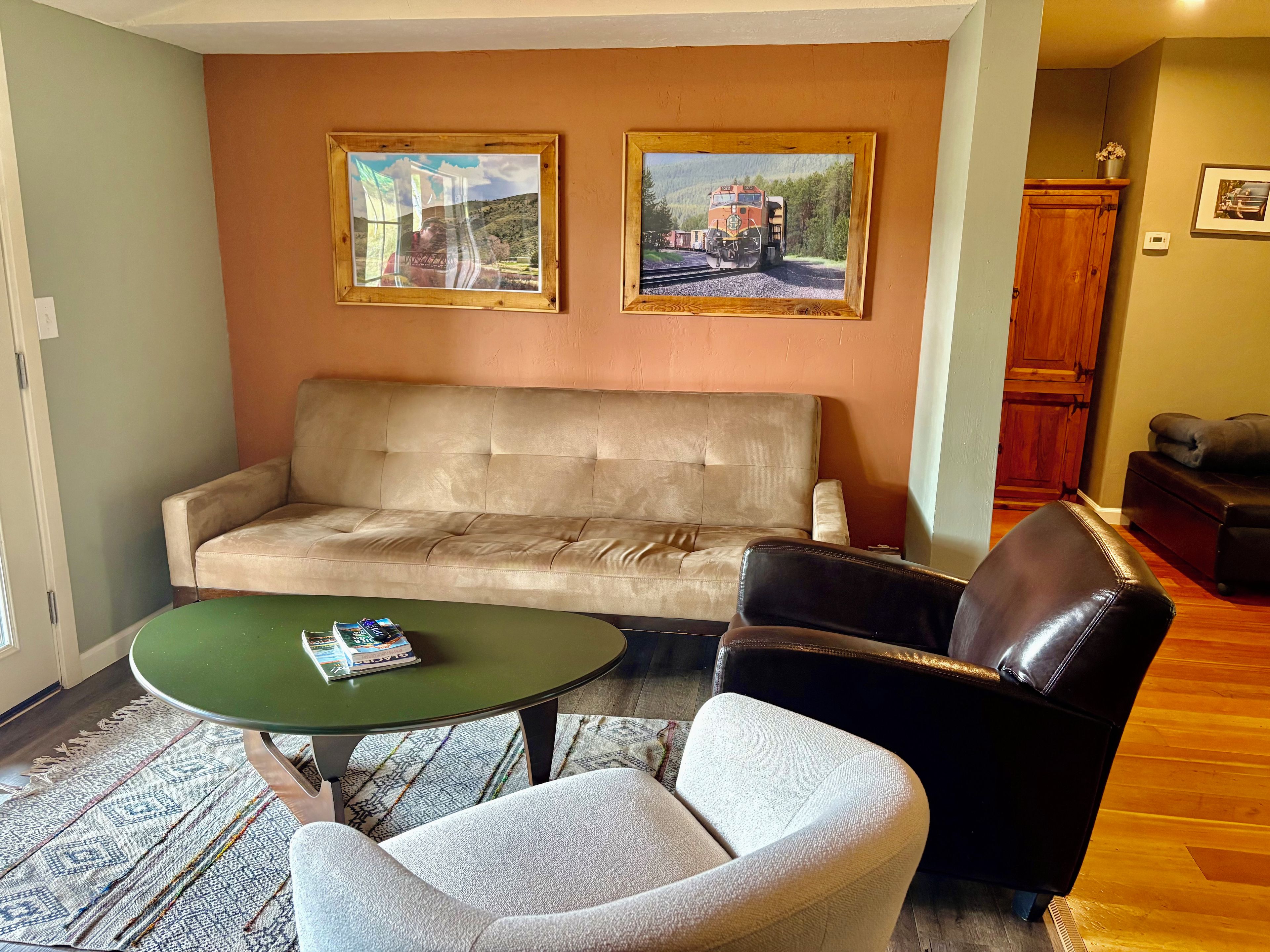 Un salon comprenant un canapé, deux fauteuils, une table basse et deux tableaux encadrés accrochés au mur.