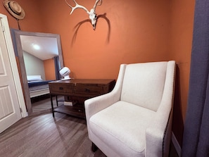 A room with a bed, a dresser, a mirror, and a wall-mounted deer skull.