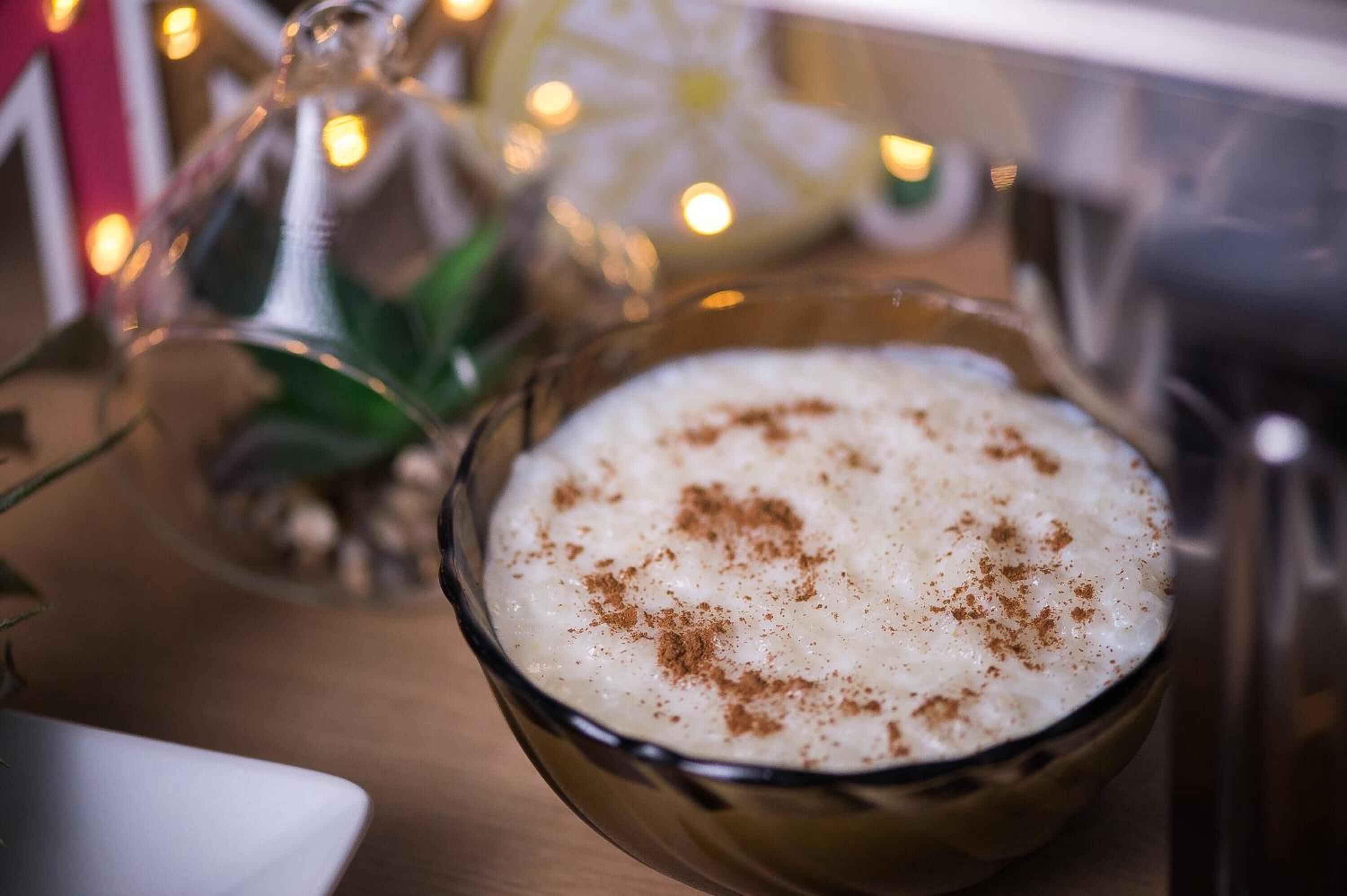 A bowl of rice pudding with cinnamon on a wooden table.