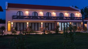 Ein modernes, zweistöckiges Haus mit rotem Ziegeldach, großen Fenstern und einer gut beleuchteten Fassade.