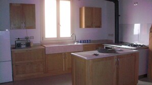 A kitchen with wooden cabinets, a central island, a window with blinds, and a stove.