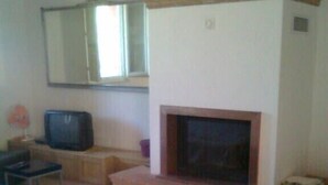 A living room with a fireplace, a television, and a sofa.