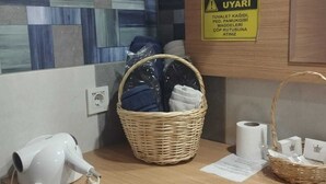 Un espace d’accueil d’hôtel équipé d’un sèche-cheveux, d’un panier de serviettes et d’un panneau d’avertissement accroché au mur.