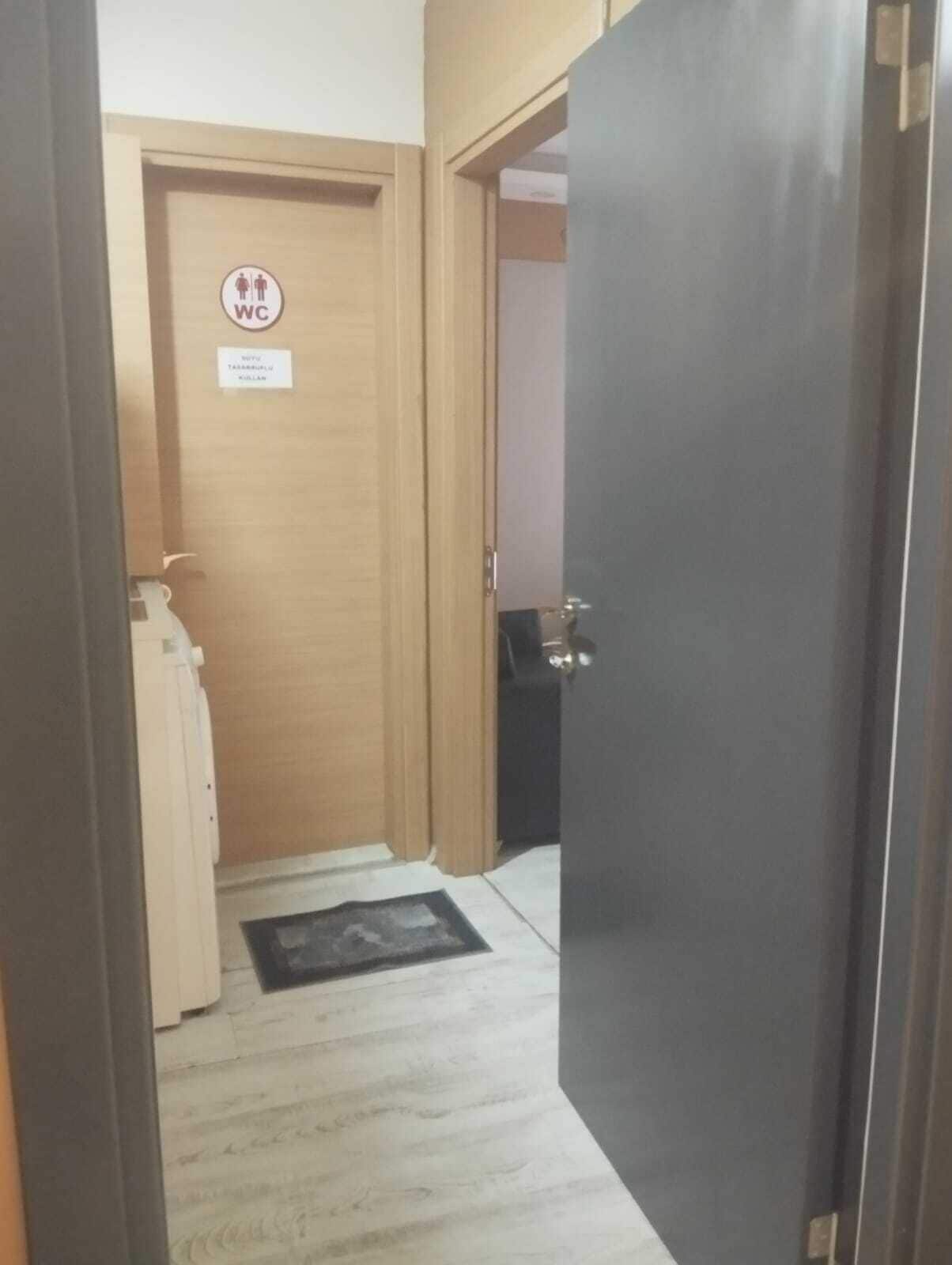 Un pasillo estrecho con una puerta de madera que indica “WC” y un cartel que señala una zona para fumadores.