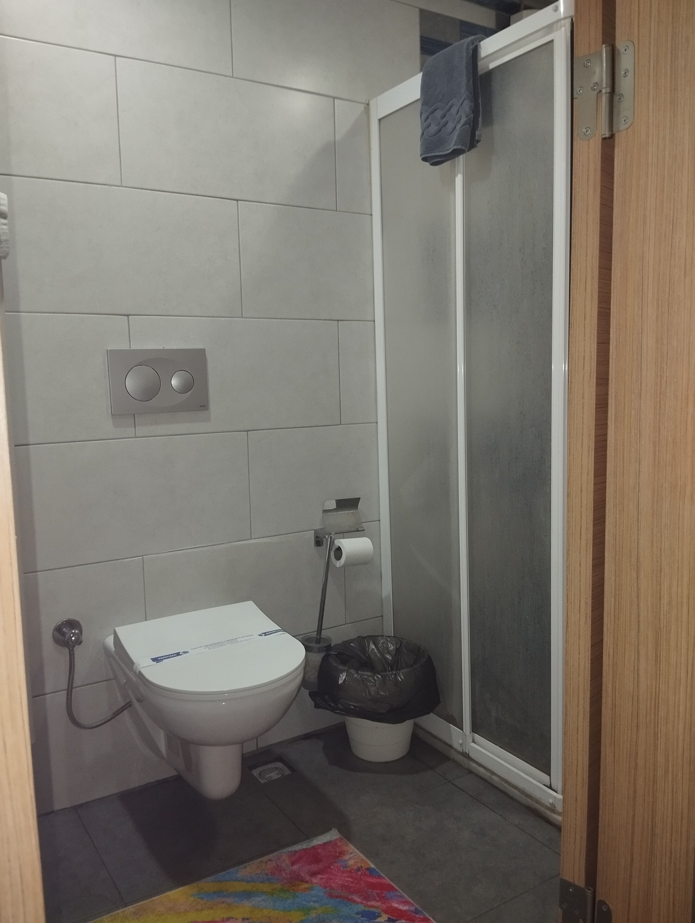 Une petite salle de bain comprenant des toilettes, une douche et un porte-rouleau de papier toilette.
