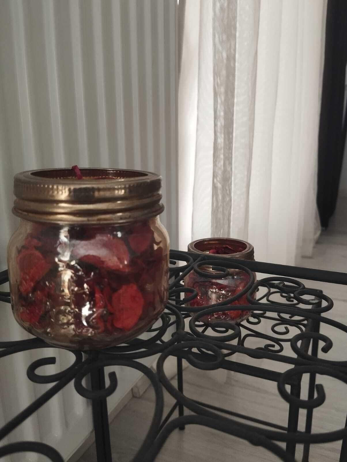 Ein Glasgefäß, gefüllt mit roten Gegenständen, auf einem Metalltisch mit dekorativer Verzierung.