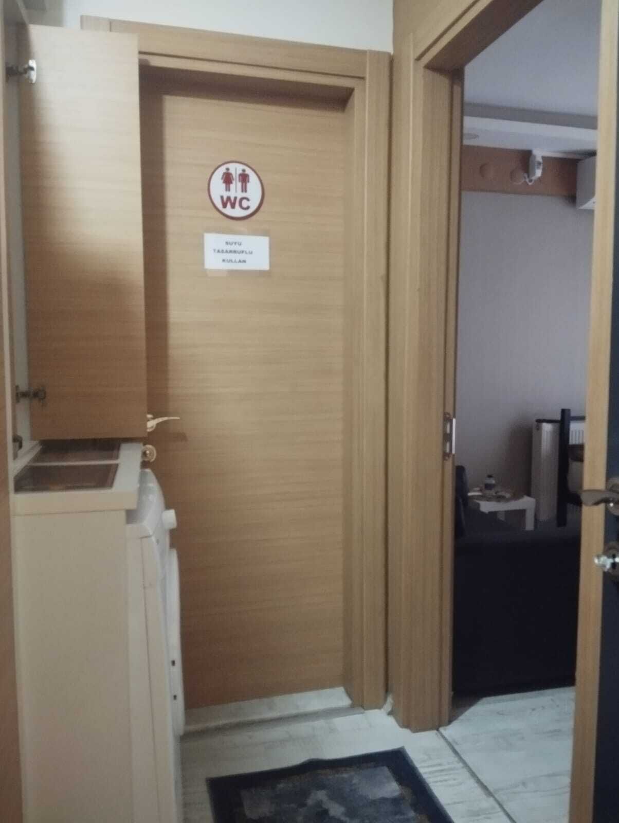Una puerta de madera con un letrero de WC y una señal en un idioma extranjero.