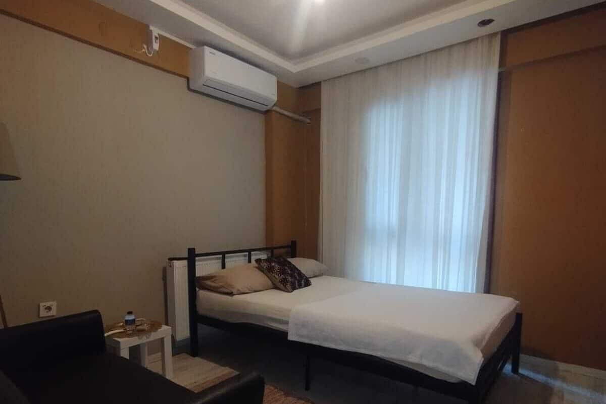 Ein Hotelzimmer mit Bett, einem kleinen Tisch, einem Stuhl und einer Klimaanlage.