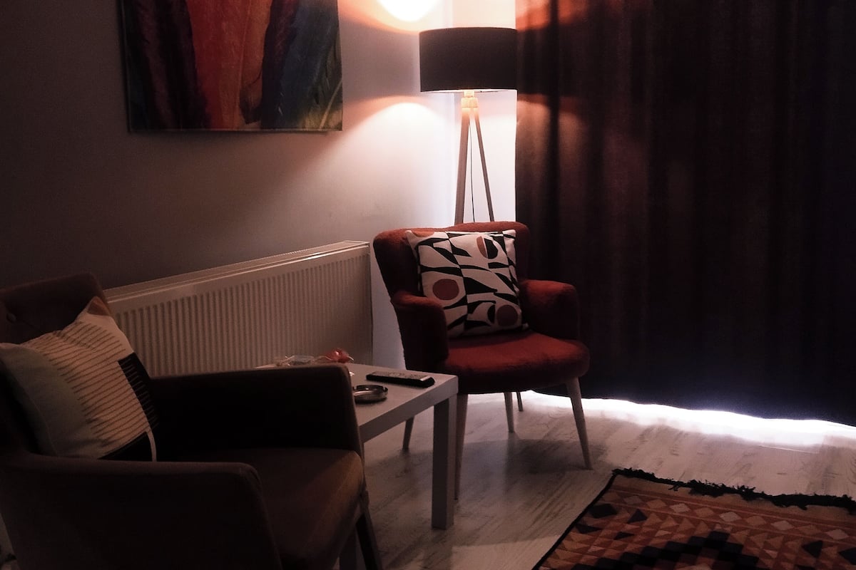 Ein Wohnzimmer mit Sofa, Sesseln, einer Stehlampe und einem Bild an der Wand.