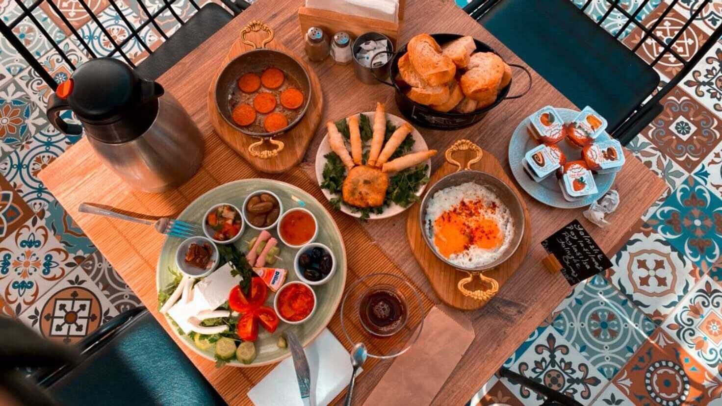 Una mesa de comedor con diferentes platos, un termo y condimentos.