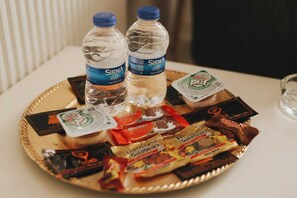 Een dienblad met waterflesjes, snacks en een kaartje op een tafel.