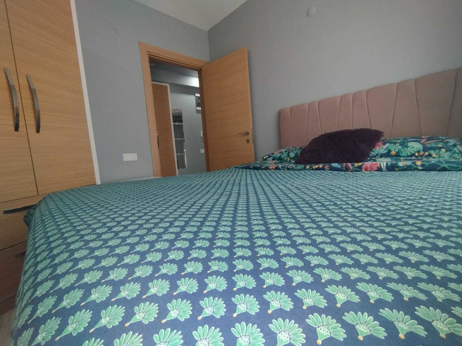 A bedroom with a bed, a wardrobe, and a door leading to another room.