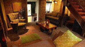 A cozy living room with a stone fireplace, a wooden coffee table, and a comfortable sofa. - The Lodge Rooms (Coleford)
