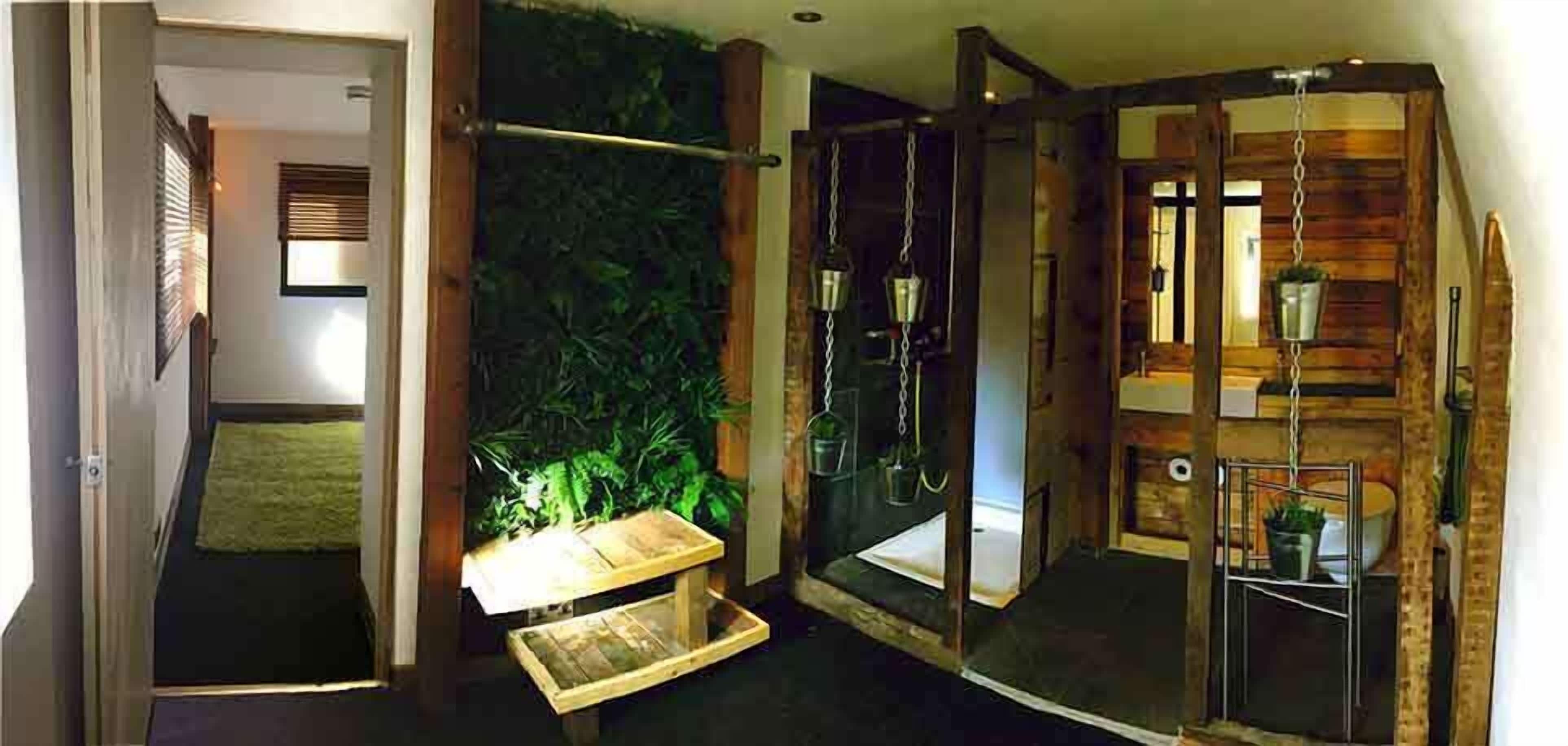Un baño con cabina de ducha de madera, una mesita pequeña de madera y una planta en maceta.