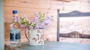 Uma garrafa de água mineral LITZ e uma caneca de cerâmica com um desenho floral sobre uma mesa de madeira.
