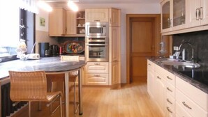 Uma cozinha moderna com armários de madeira, forno de aço inoxidável e bancada preta.