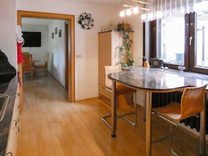 Un coin repas avec une table et des chaises en verre, un meuble en bois et une plante.