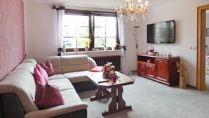 Uma sala de estar com sofá, mesa de centro, televisão e radiador.