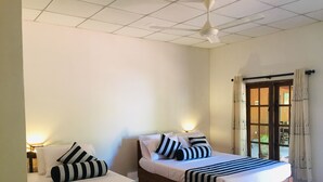 A room with two beds, each with striped bedding and pillows, a ceiling fan, and a window with curtains. - Jaye Eco Lodge (Habarana)