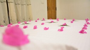 A bed with a white sheet and pink flower petals scattered on it. - Jaye Eco Lodge (Habarana)