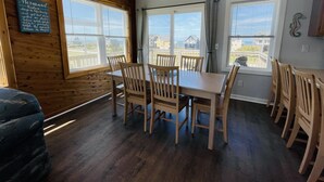Un comedor con mesas y sillas de madera, ventanas amplias con cortinas y vistas al exterior.