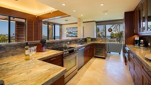 Una cocina moderna con encimeras de granito, electrodomésticos de acero inoxidable y vistas al océano.