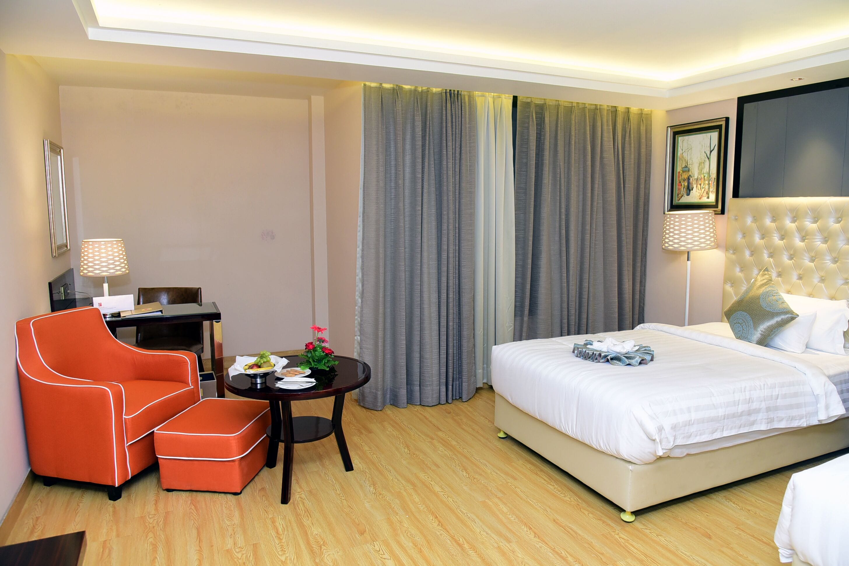 Una habitación de hotel con una cama, una silla, una mesita con lámpara y un escritorio.