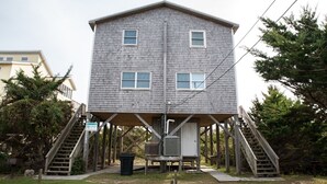 Un bâtiment à deux étages doté d’une terrasse en bois et d’un escalier menant à l’entrée.