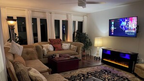 A living room with a sofa set, a coffee table, a fireplace, and a television mounted on the wall. - Bloomington Indiana Rental- 3BR/2BA Apartment in upper level of duplex (Bloomington)