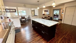 A modern kitchen with dark wood flooring, a central island, and pendant lighting. - Bloomington Indiana Rental- 3BR/2BA Apartment in upper level of duplex (Bloomington)