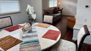 A dining area with a round table, chairs, and a vase of flowers. There is a sofa and a lamp in the background. - Bloomington Indiana Rental- 3BR/2BA Apartment in upper level of duplex (Bloomington)