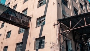 Un immeuble à plusieurs étages présentant des dommages structurels apparents et dont les câbles électriques sont à découvert.