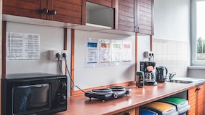 Une cuisine avec des meubles en bois, un four à micro-ondes, une machine à café et des poubelles.