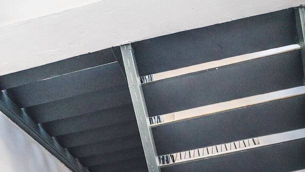 Un escalier avec des rampes en métal et une main courante noire.