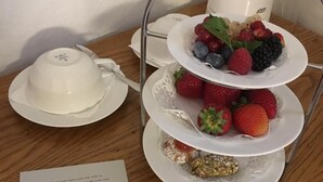 Ett fruktfat i tre våningar med jordgubbar, blåbär och hallon, en vit tekanna och ett tackkort från den överordnade chefen.