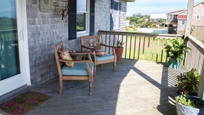 Une terrasse en bois avec deux chaises et des plantes en pot.