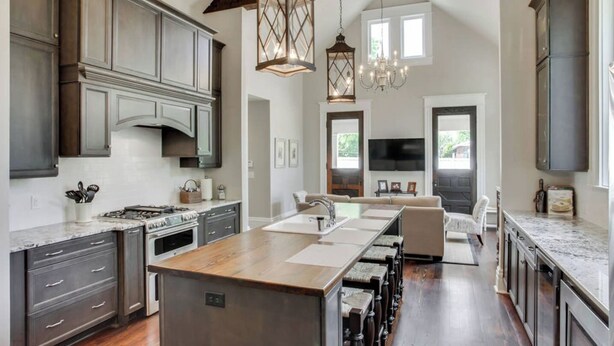 A spacious kitchen with dark cabinetry, a central island, and a dining area with a sofa. - Southern Stunners - Large Group Luxury (Nashville)