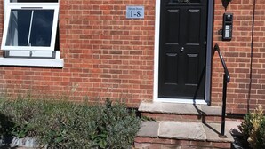 A brick building with a black door, a window, and a sign reading "Helena House 1-8". - Flat 1 Helena House, 1-bed, Sleeps 2, Garden (Reading)