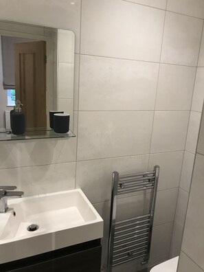 A modern bathroom with a white sink, a mirror, and a towel rack. - Flat 1 Helena House, 1-bed, Sleeps 2, Garden (Reading)