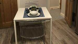 A small dining area with a white table, clear chair, and a few potted plants. - Flat 1 Helena House, 1-bed, Sleeps 2, Garden (Reading)