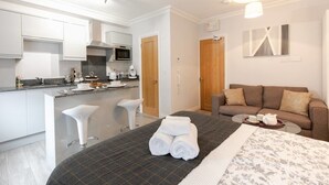 Et moderne hotelværelse med tekøkken, sofa og seng med pænt sengelinned.