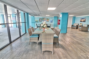 A room with a glass wall, wicker furniture, and a table with a vase. - Oceanfront Waterpointe1 606-3b/2b-Sleep6-Balcony-WIFI-TV-Pool-Family Friendly (North Myrtle Beach)