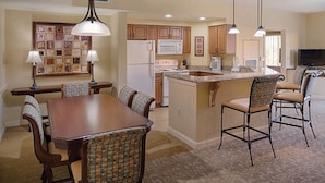 A spacious kitchen with wooden cabinets, a central island, and a dining area with a table and chairs.