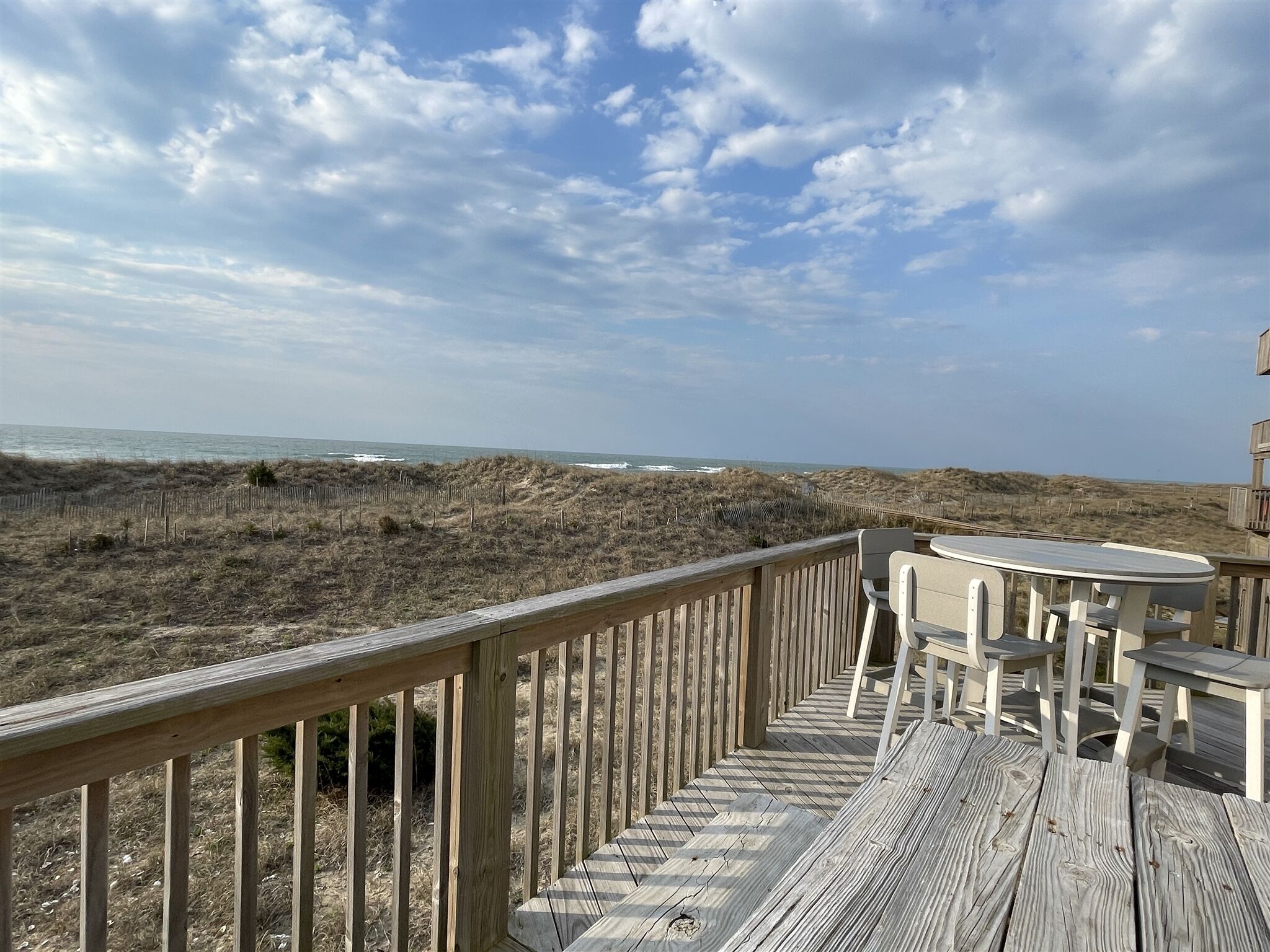 A wooden deck with a view of the beach and dunes.