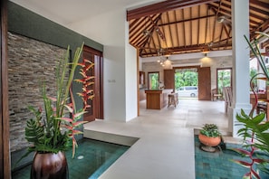 Enter a serene space with a stone wall, wooden reception desk, and lush greenery.