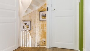 A staircase with white railings leading to a room with a white door and a green wall. - Le Passage - bright apartment with terrace (Albi)